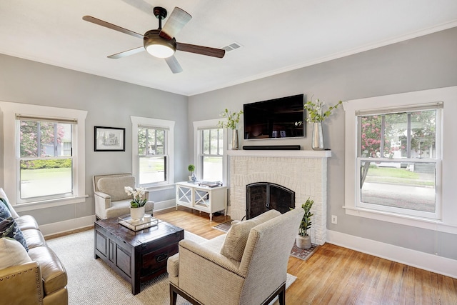 936 W Temple St, Houston, TX 77009 - living area featuring light wood finished floors, ceiling fan, a brick fireplace, and crown molding