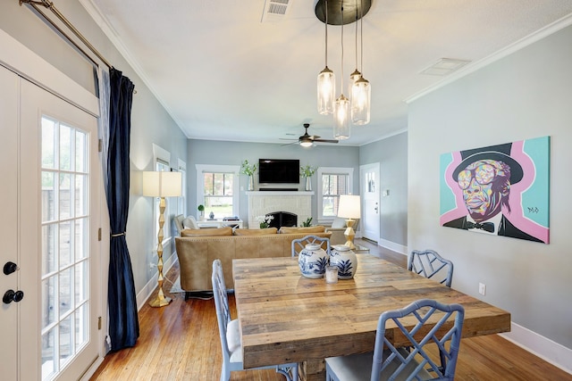 936 W Temple St, Houston, TX 77009 - dining room with a brick fireplace, a ceiling fan, light wood-style floors, and ornamental molding