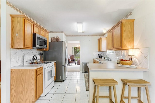2210 Elm Forest Dr, Pearland, TX 77584 - kitchen with appliances with stainless steel finishes, backsplash, light countertops, and a peninsula