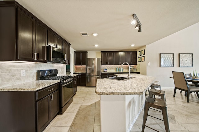 29023 Jacobs River Dr, Katy, TX 77494 - kitchen featuring appliances with stainless steel finishes, a kitchen breakfast bar, decorative backsplash, a center island with sink, and light tile patterned floors