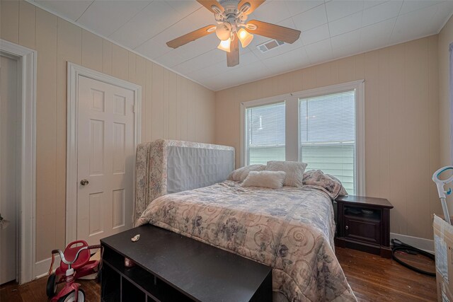 604 Abell St, Wharton, TX 77488 - bedroom featuring dark wood-style floors, a ceiling fan, and wooden walls