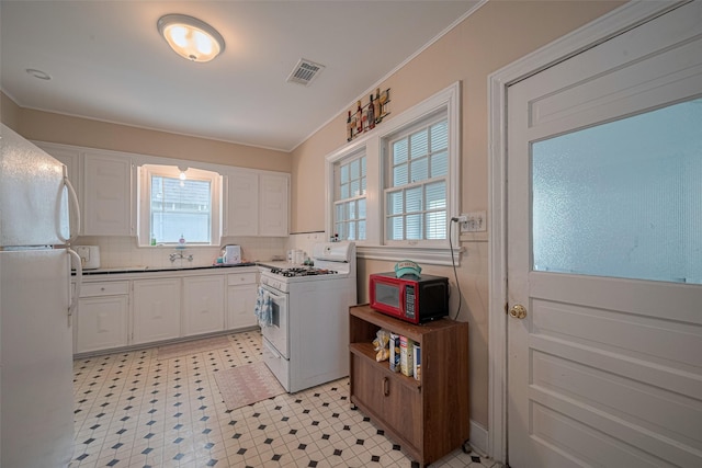 604 Abell St, Wharton, TX 77488 - kitchen featuring white appliances, white cabinetry, healthy amount of natural light, and crown molding