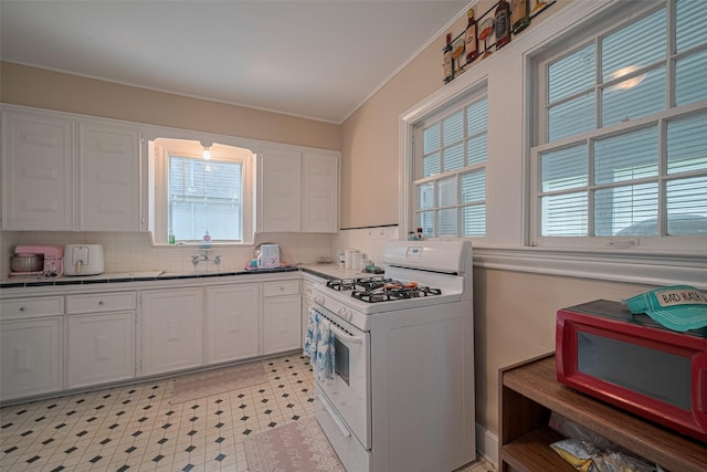604 Abell St, Wharton, TX 77488 - kitchen with white gas range, white cabinets, crown molding, tasteful backsplash, and light flooring