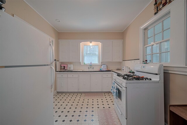 604 Abell St, Wharton, TX 77488 - kitchen with white appliances, white cabinets, crown molding, light flooring, and tasteful backsplash
