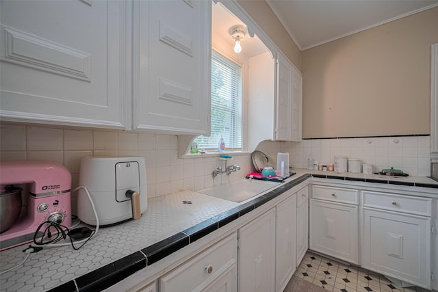 604 Abell St, Wharton, TX 77488 - kitchen with white cabinetry, tile counters, tasteful backsplash, ornamental molding, and light floors