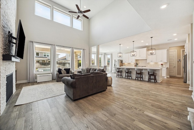 19526 Rock Quillwort Rd, Cypress, TX 77433 - living area featuring a ceiling fan, a stone fireplace, light wood finished floors, recessed lighting, and a high ceiling