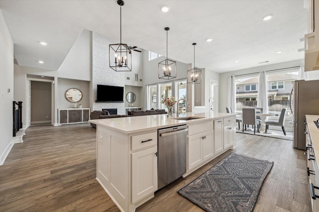 19526 Rock Quillwort Rd, Cypress, TX 77433 - kitchen with stainless steel appliances, white cabinets, a center island with sink, wood finished floors, and pendant lighting