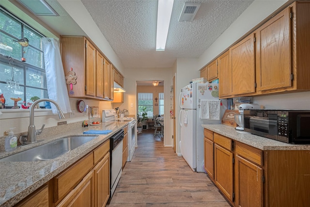 2017 Willow Bend Rd, Wharton, TX 77488 - kitchen featuring white appliances, light wood-style flooring, a textured ceiling, and brown cabinets