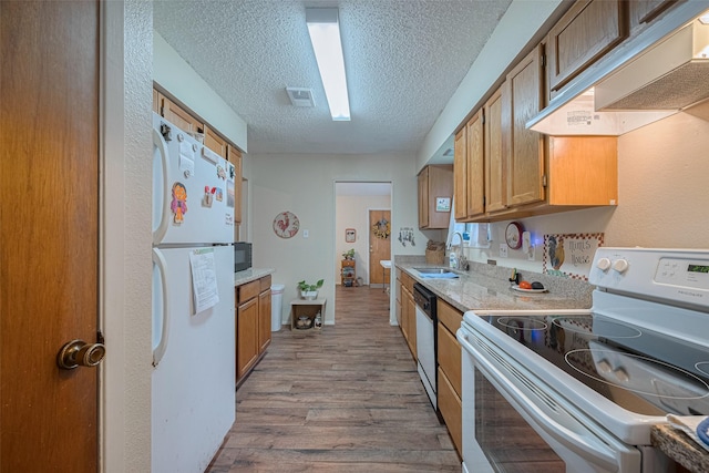 2017 Willow Bend Rd, Wharton, TX 77488 - kitchen featuring white appliances, a textured ceiling, wood finished floors, brown cabinetry, and under cabinet range hood