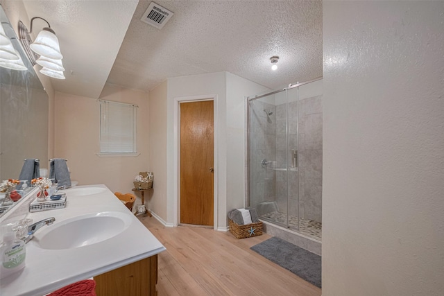 2017 Willow Bend Rd, Wharton, TX 77488 - bathroom featuring wood finished floors, a shower stall, double vanity, and a textured ceiling