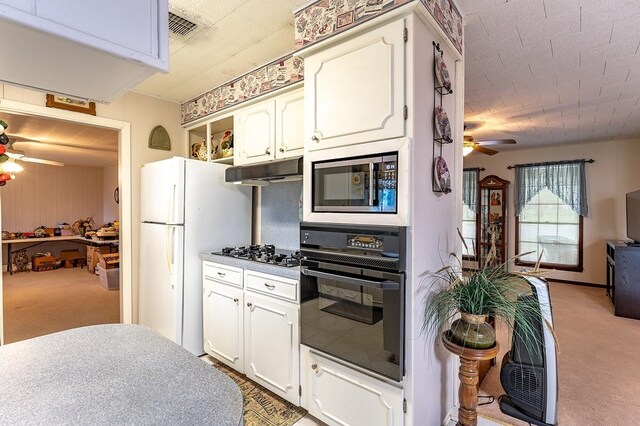 860 Helter St, La Grange, TX 78945 - kitchen with oven, ceiling fan, stainless steel microwave, freestanding refrigerator, and light carpet