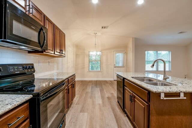 167 Courageous Side Way, Magnolia, TX 77354 - kitchen featuring black appliances, light wood finished floors, backsplash, light stone counters, and decorative light fixtures