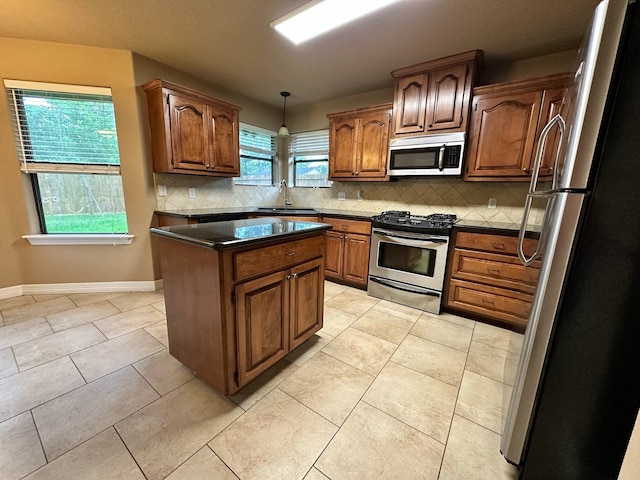 1040 Cardinal Dr, Richwood, TX 77566 - kitchen featuring appliances with stainless steel finishes, dark countertops, backsplash, a center island, and light tile patterned floors
