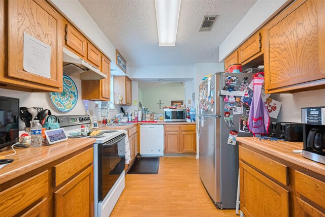 1805 Willow Bend Rd, Wharton, TX 77488 - kitchen with stainless steel appliances, light wood finished floors, a textured ceiling, under cabinet range hood, and wood counters