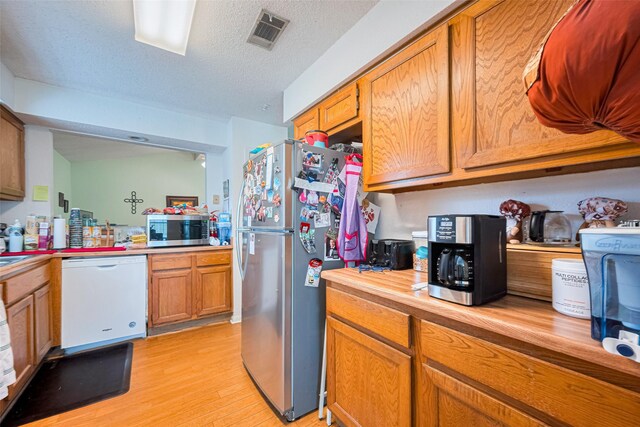 1805 Willow Bend Rd, Wharton, TX 77488 - kitchen with appliances with stainless steel finishes, light wood-type flooring, brown cabinets, a textured ceiling, and butcher block counters