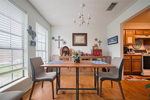 1805 Willow Bend Rd, Wharton, TX 77488 - dining space with a chandelier, light wood-style flooring, a textured ceiling, and healthy amount of natural light