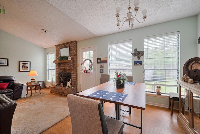 1805 Willow Bend Rd, Wharton, TX 77488 - dining room featuring a fireplace, a textured ceiling, a chandelier, light wood-style floors, and lofted ceiling