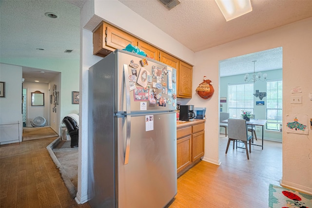 1805 Willow Bend Rd, Wharton, TX 77488 - kitchen with freestanding refrigerator, a textured ceiling, light wood-style floors, a chandelier, and light countertops