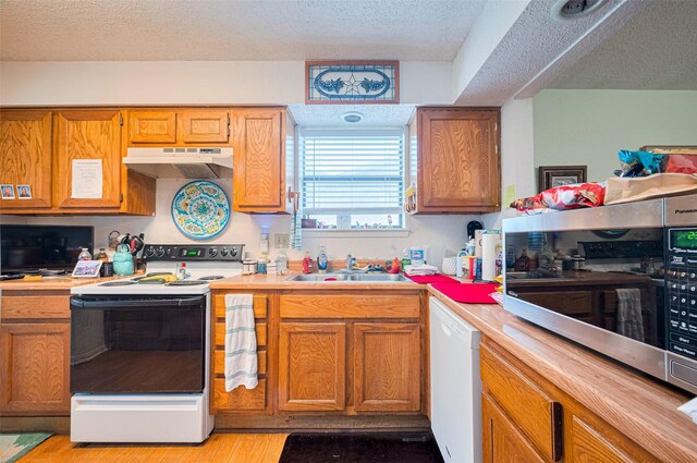 1805 Willow Bend Rd, Wharton, TX 77488 - kitchen with white appliances, under cabinet range hood, a textured ceiling, light countertops, and light wood-type flooring