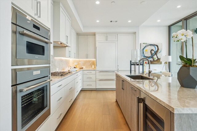 5656 San Felipe St Unit 606, Houston, TX 77056 - kitchen with stainless steel appliances, light wood-type flooring, light stone counters, recessed lighting, and white cabinetry