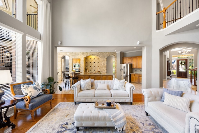 4607 Wellbrook Ln, Katy, TX 77450 - living room featuring a high ceiling, arched walkways, a chandelier, and light wood finished floors