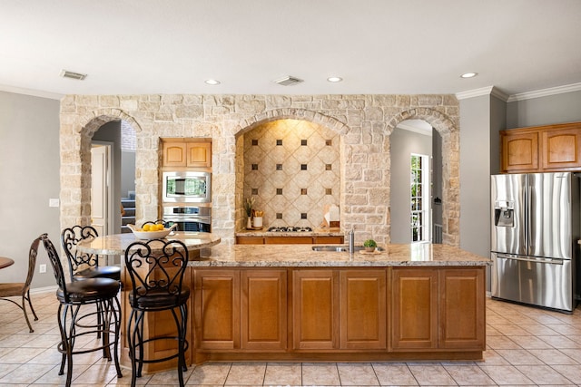 4607 Wellbrook Ln, Katy, TX 77450 - kitchen featuring stainless steel appliances, arched walkways, light stone countertops, light tile patterned floors, and ornamental molding