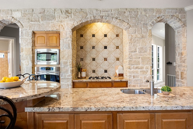 4607 Wellbrook Ln, Katy, TX 77450 - kitchen with appliances with stainless steel finishes, crown molding, light stone counters, backsplash, and arched walkways