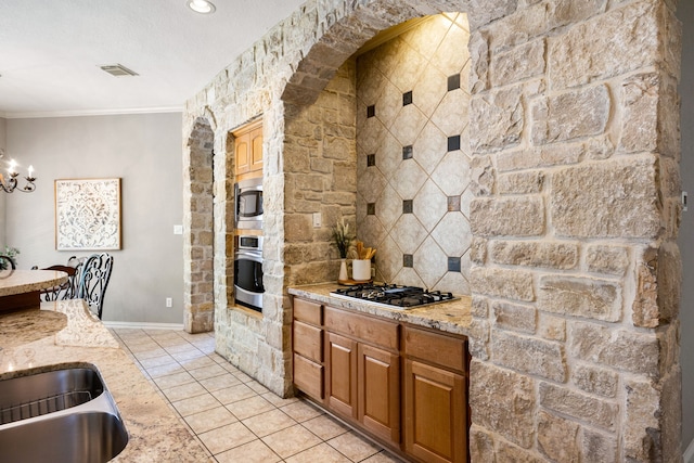 4607 Wellbrook Ln, Katy, TX 77450 - kitchen featuring appliances with stainless steel finishes, a chandelier, light stone counters, ornamental molding, and light tile patterned flooring