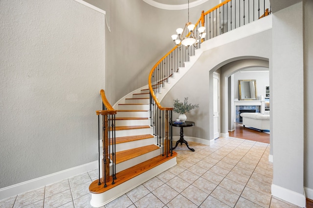 4607 Wellbrook Ln, Katy, TX 77450 - stairway with arched walkways, tile patterned floors, a chandelier, a high ceiling, and a fireplace