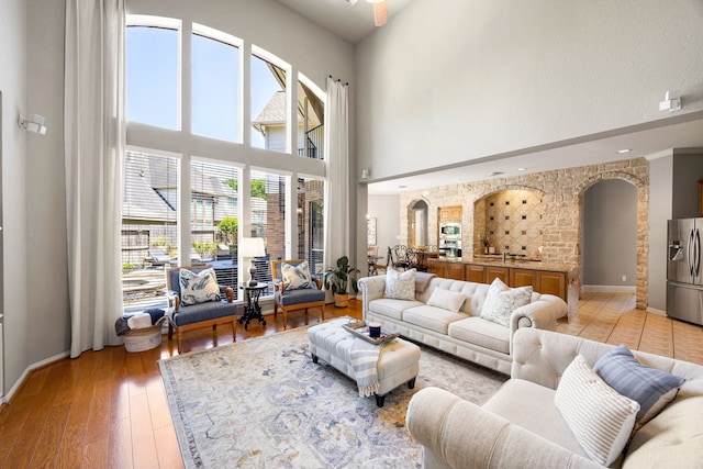 4607 Wellbrook Ln, Katy, TX 77450 - living room featuring a towering ceiling, arched walkways, and light wood-style flooring