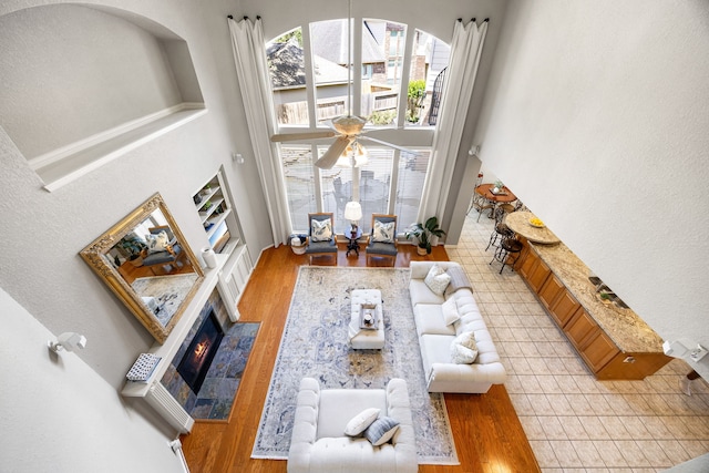 4607 Wellbrook Ln, Katy, TX 77450 - living room with a tiled fireplace, a towering ceiling, light wood-style flooring, and ceiling fan