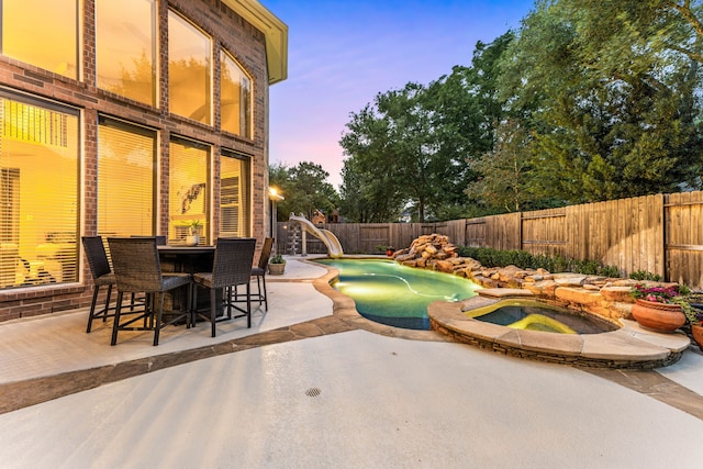 4607 Wellbrook Ln, Katy, TX 77450 - patio terrace at dusk featuring a patio area, an in-ground hot tub, and a fenced backyard