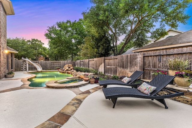 4607 Wellbrook Ln, Katy, TX 77450 - patio terrace at dusk featuring a patio area, a fenced backyard, and a pool with connected hot tub