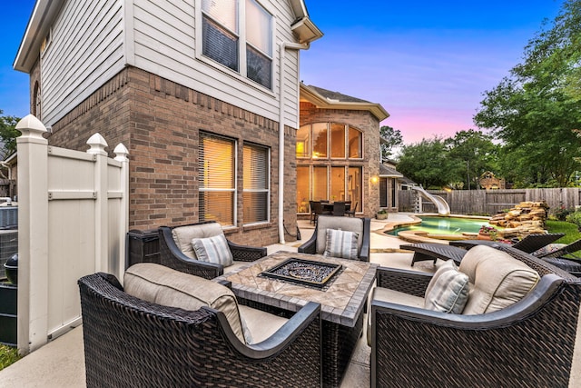 4607 Wellbrook Ln, Katy, TX 77450 - patio terrace at dusk with an outdoor living space with a fire pit, a patio area, and a fenced backyard