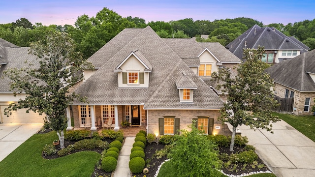 4607 Wellbrook Ln, Katy, TX 77450 - view of front facade with driveway, a shingled roof, brick siding, covered porch, and a lawn