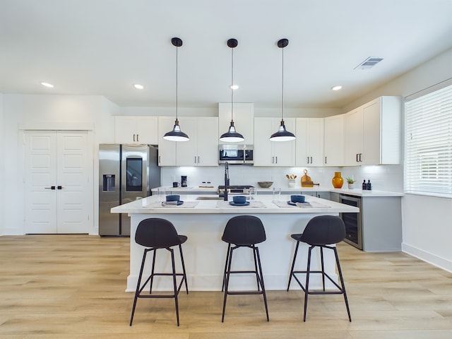 8319 Springwood Canyon Ln, Houston, TX 77055 - kitchen featuring appliances with stainless steel finishes, beverage cooler, a breakfast bar, light wood finished floors, and recessed lighting