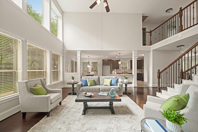 12102 N Founders Shore Dr, Cypress, TX 77433 - living area featuring ornate columns, a ceiling fan, dark wood finished floors, a high ceiling, and stairs