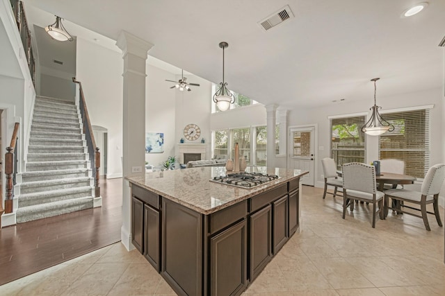 12102 N Founders Shore Dr, Cypress, TX 77433 - kitchen with ornate columns, stainless steel gas cooktop, a ceiling fan, and dark brown cabinetry