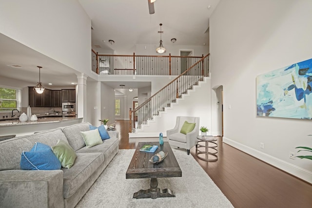12102 N Founders Shore Dr, Cypress, TX 77433 - living area with wood finished floors, a towering ceiling, stairway, ceiling fan, and ornate columns