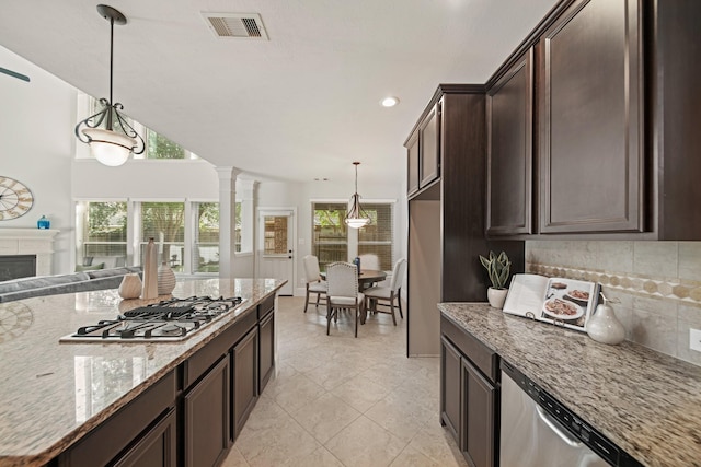 12102 N Founders Shore Dr, Cypress, TX 77433 - kitchen with appliances with stainless steel finishes, dark brown cabinetry, backsplash, light stone countertops, and decorative columns