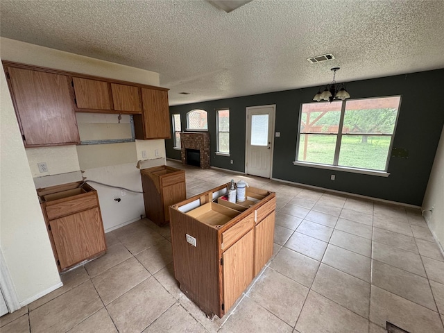 1629 Sylvia Ct, Round Rock, TX 78681 - kitchen with a chandelier, a fireplace, light tile patterned floors, a textured ceiling, and decorative light fixtures
