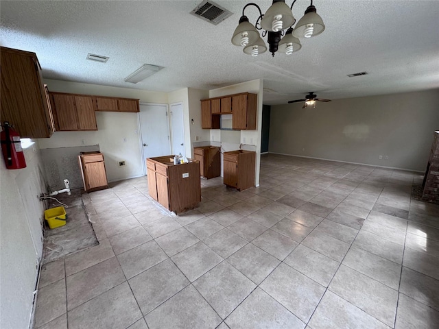 1629 Sylvia Ct, Round Rock, TX 78681 - kitchen with open floor plan, brown cabinetry, a chandelier, a kitchen island, and a textured ceiling