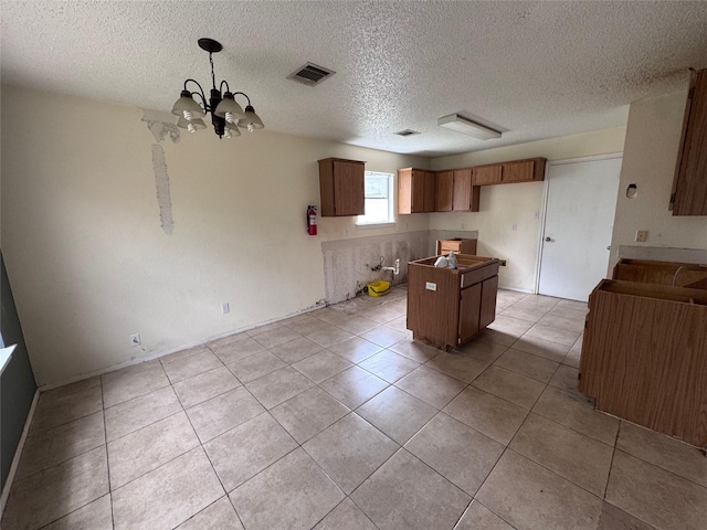 1629 Sylvia Ct, Round Rock, TX 78681 - kitchen with a chandelier, a textured ceiling, light tile patterned flooring, a center island, and pendant lighting