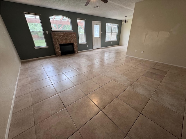 1629 Sylvia Ct, Round Rock, TX 78681 - unfurnished living room featuring a textured ceiling, ceiling fan, tile patterned flooring, and a fireplace