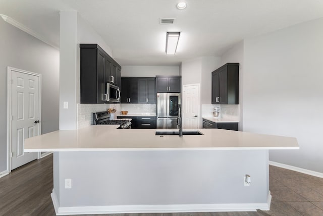 38318 E Sulphur Creek Dr, Magnolia, TX 77355 - kitchen with stainless steel appliances, light countertops, tasteful backsplash, a peninsula, and dark cabinets