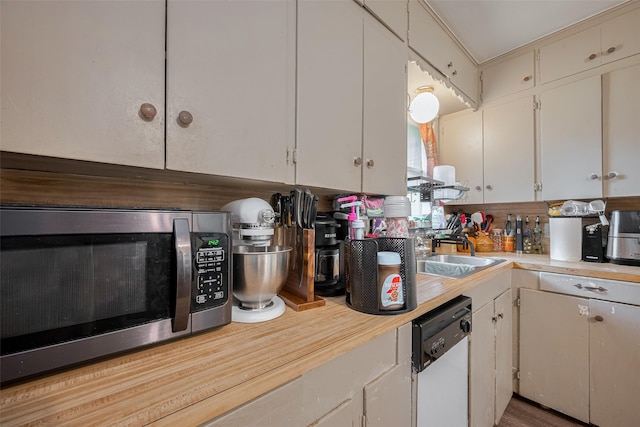 513 Frankie St, Wharton, TX 77488 - kitchen with stainless steel microwave, white dishwasher, light countertops, and white cabinetry