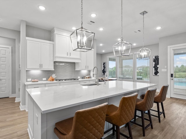 21310 Blue Wood Aster Ct, Cypress, TX 77433 - kitchen with stainless steel gas cooktop, a chandelier, a kitchen island with sink, backsplash, and healthy amount of natural light