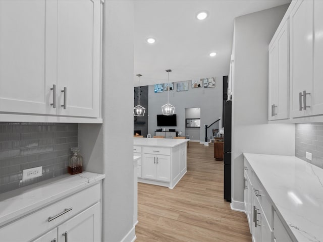 21310 Blue Wood Aster Ct, Cypress, TX 77433 - kitchen featuring white cabinets, open floor plan, tasteful backsplash, light wood finished floors, and light stone countertops
