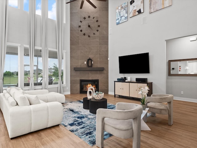 21310 Blue Wood Aster Ct, Cypress, TX 77433 - living area with a towering ceiling, ceiling fan, a tile fireplace, and wood finished floors