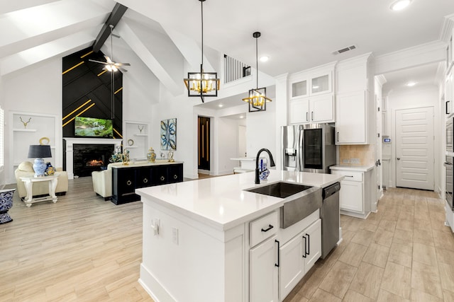 6523 Poplar Meadow Ln, Katy, TX 77493 - kitchen with stainless steel appliances, a center island with sink, open floor plan, a lit fireplace, and light countertops